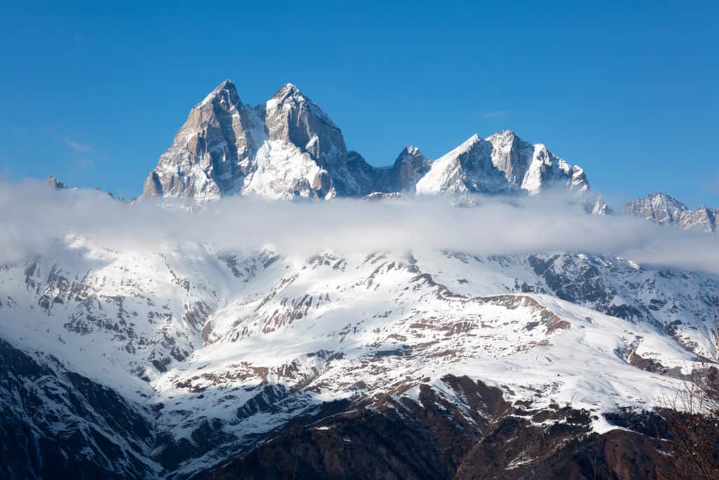 Mount Ushba in Georgien, schneebedeckt über den Wolken.